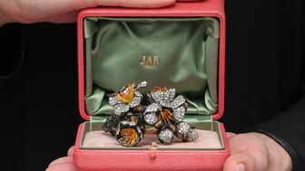 A signed diamond “Apricot Blossom” bangle by JAR, circa 2009, featuring diamonds, reddish-orange and yellow enamel, blackened silver, yellow gold, and bronze, with a pink JAR case. The bracelet, estimated to fetch up to $570,000, will lead the sale of a collection of jewels by JAR at Christie’s Geneva on May 14. JAR Apricot Blossom bracelet