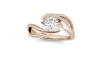 A 14-karat rose gold swirl bypass solitaire engagement ring set with a 1.10-carat “Forever One” cushion-cut moissanite by Charles & Colvard. The company has been delisted from the Nasdaq stock exchange after failing to file its annual report on time. Charles & Colvard moissanite ring