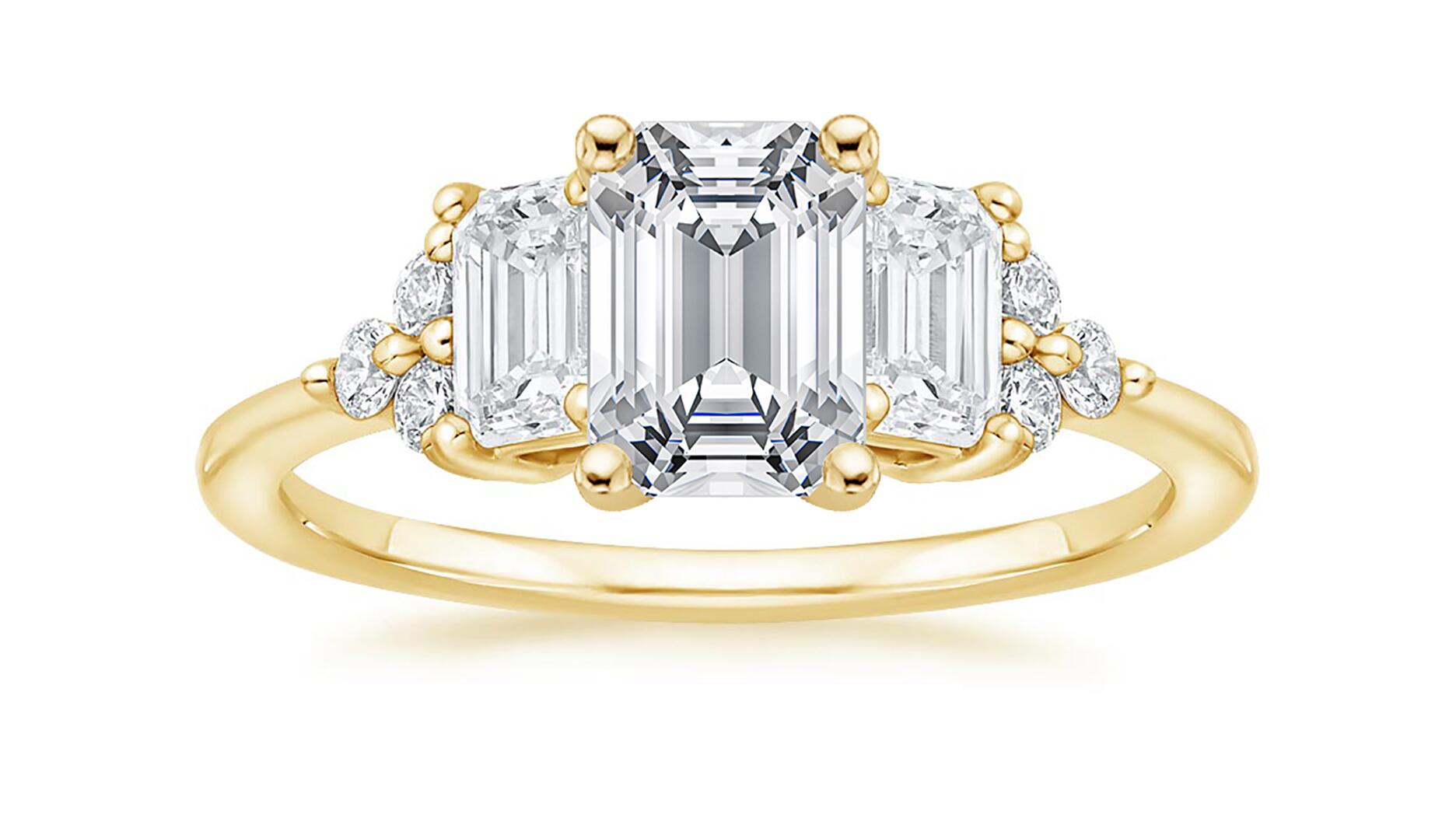 The “Sabine” cluster diamond engagement ring in 18-karat yellow gold with two emerald-cut diamonds and a cluster of round diamonds ($3,590, setting only) from Brilliant Earth’s “Mosaics” collection. The jewelry retailer saw sales decline 4 percent in the first quarter. Brilliant Earth three stone Sabine diamond engagement ring