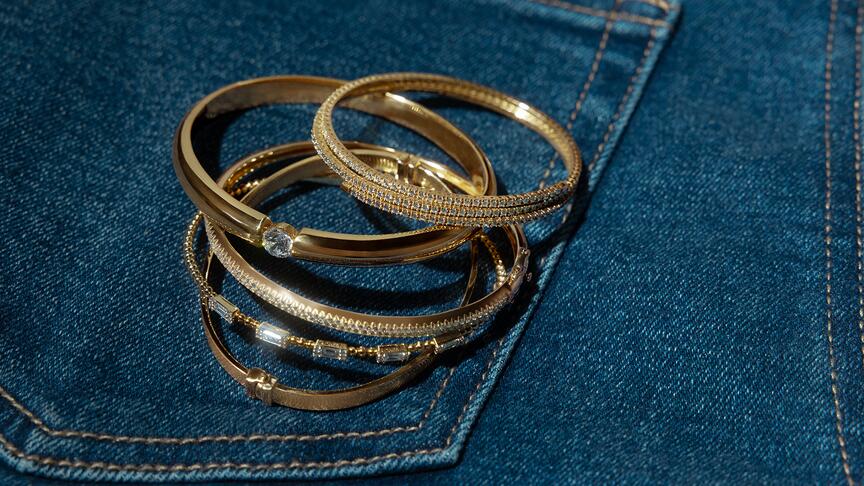Gold and diamond bangles on a pair of jeans